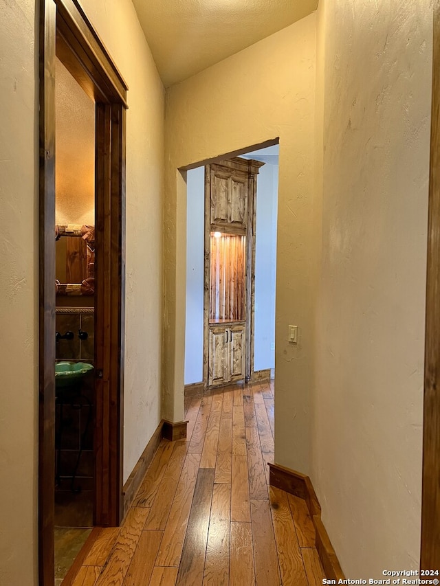 hallway featuring light hardwood / wood-style floors and vaulted ceiling