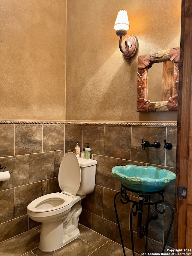 bathroom featuring sink, tile walls, toilet, and tile patterned floors