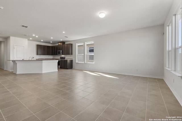 unfurnished living room featuring light tile patterned floors, recessed lighting, a sink, visible vents, and baseboards