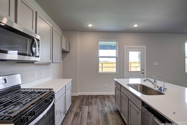 kitchen with appliances with stainless steel finishes, dark hardwood / wood-style flooring, gray cabinetry, a textured ceiling, and sink