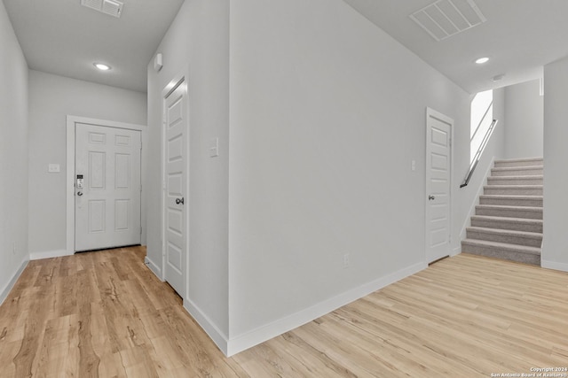 hallway featuring stairway, baseboards, visible vents, and light wood-style floors