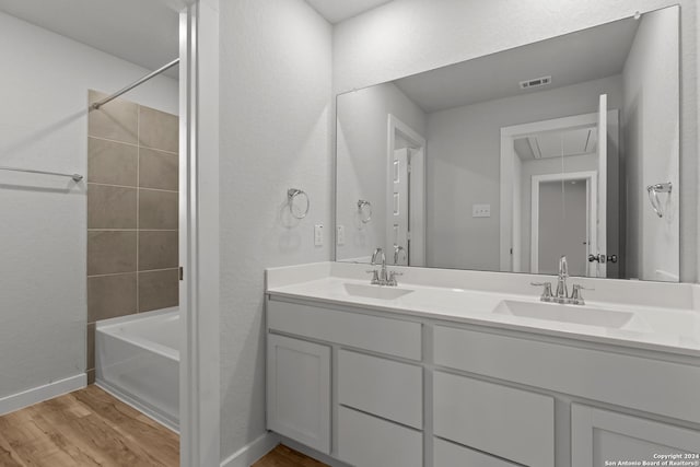 bathroom with hardwood / wood-style floors, vanity, and tiled shower / bath