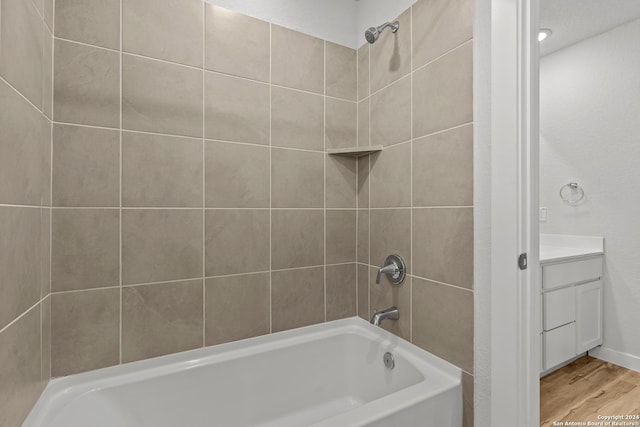 bathroom with hardwood / wood-style floors, vanity, and tiled shower / bath