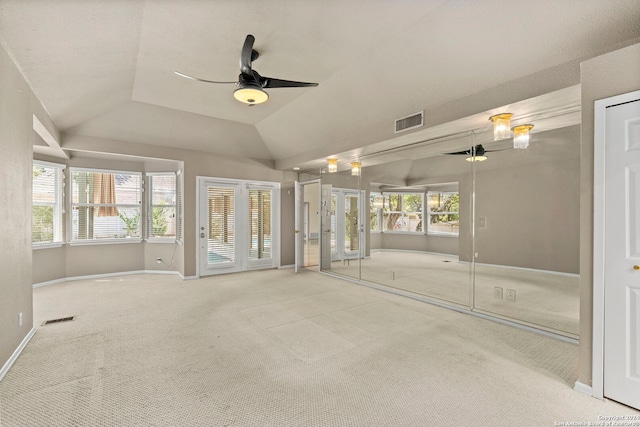 carpeted empty room with ceiling fan, vaulted ceiling, visible vents, and baseboards