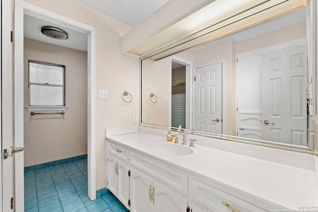 bathroom featuring tile patterned flooring, baseboards, a textured ceiling, and vanity