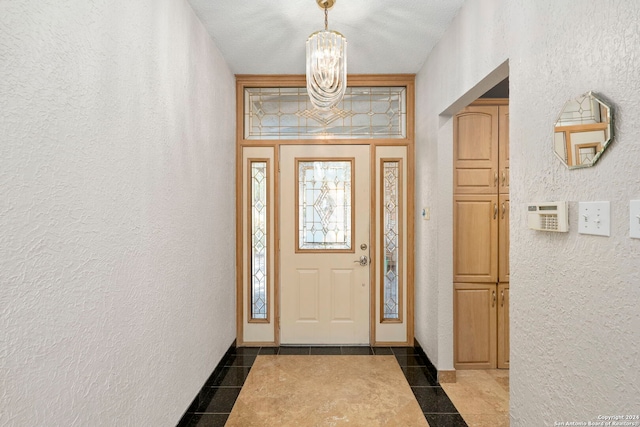 foyer entrance featuring a textured wall and a notable chandelier