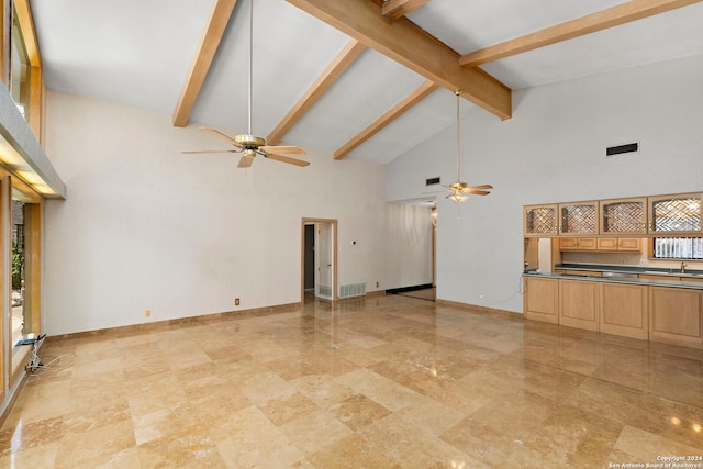 unfurnished living room featuring high vaulted ceiling, beam ceiling, baseboards, and a ceiling fan