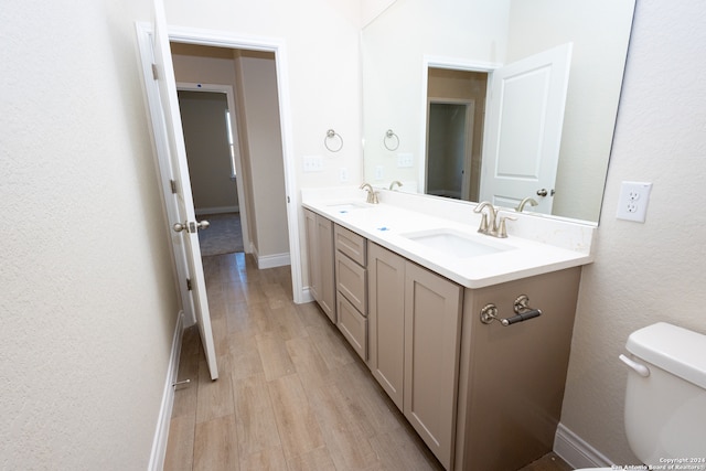 bathroom featuring double sink vanity, hardwood / wood-style flooring, and toilet