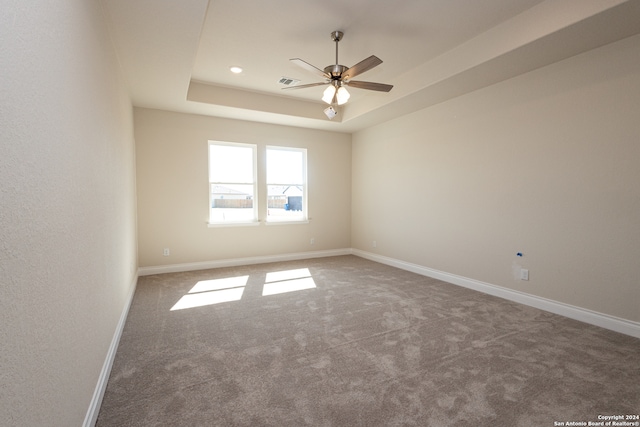 unfurnished room with ceiling fan, carpet flooring, and a tray ceiling