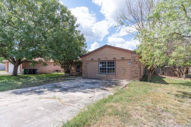 ranch-style house featuring a front yard, driveway, and fence