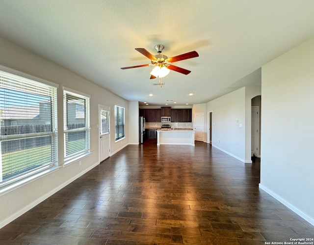 unfurnished living room with ceiling fan and dark wood-type flooring