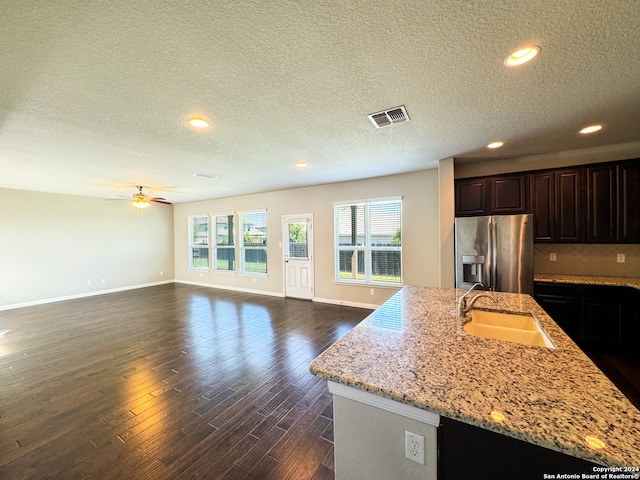 kitchen featuring ceiling fan, stainless steel refrigerator with ice dispenser, dark hardwood / wood-style flooring, light stone counters, and sink