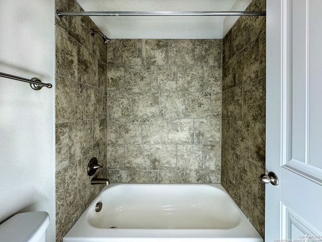 bathroom featuring tiled shower / bath combo and toilet