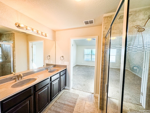 bathroom with walk in shower, a textured ceiling, tile patterned flooring, and vanity