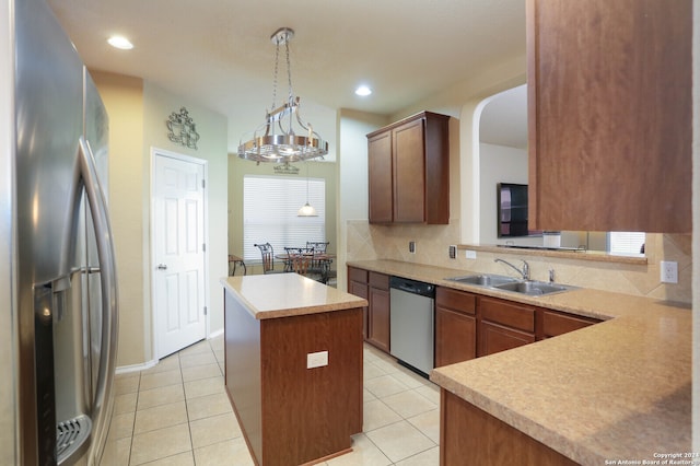 kitchen with sink, appliances with stainless steel finishes, decorative light fixtures, a kitchen island, and a notable chandelier