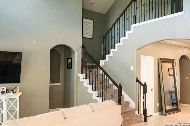 stairs with a towering ceiling and tile patterned floors