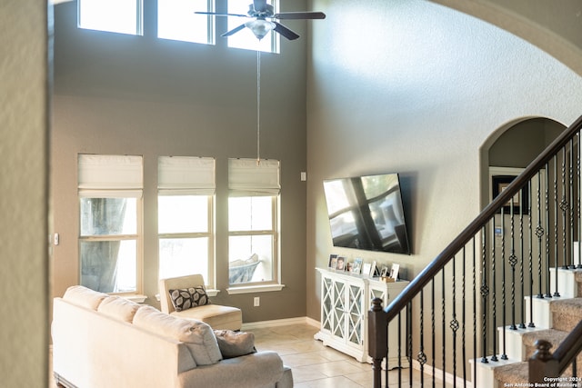 living room with ceiling fan, light tile patterned floors, and a towering ceiling