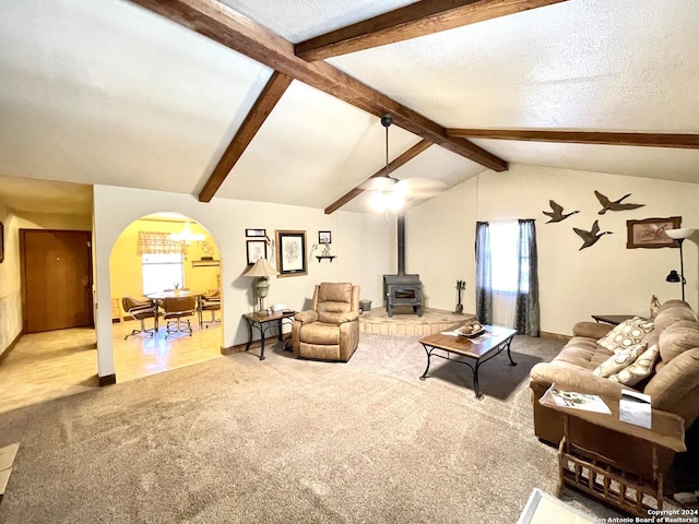 living room featuring a wood stove, carpet flooring, lofted ceiling with beams, and a textured ceiling