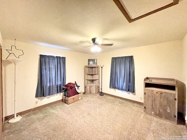 miscellaneous room with ceiling fan, a textured ceiling, and carpet flooring