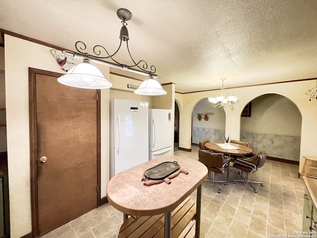 kitchen featuring crown molding, hanging light fixtures, white refrigerator, a chandelier, and a textured ceiling