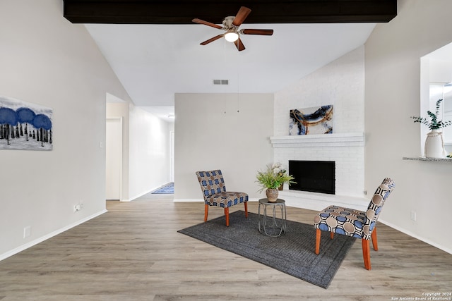 sitting room featuring beam ceiling, high vaulted ceiling, wood-type flooring, ceiling fan, and a brick fireplace