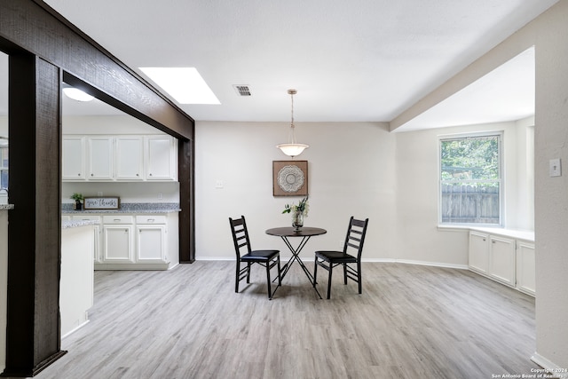 dining area featuring a skylight and light hardwood / wood-style flooring