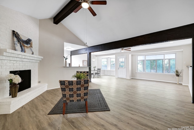 living room featuring ceiling fan, lofted ceiling with beams, light hardwood / wood-style flooring, and a fireplace