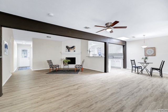 living room featuring ceiling fan, a fireplace, and light hardwood / wood-style floors