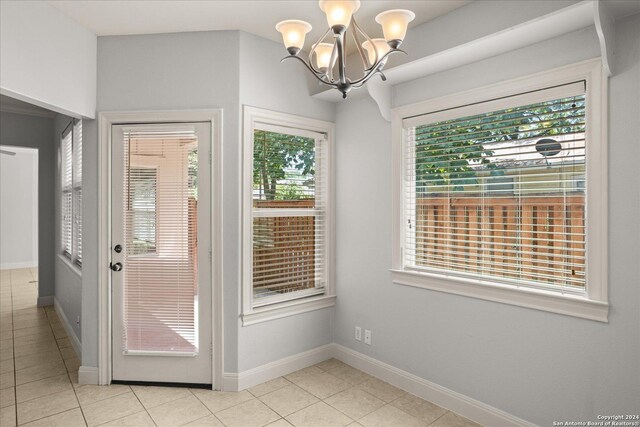 doorway with a notable chandelier and light tile patterned flooring