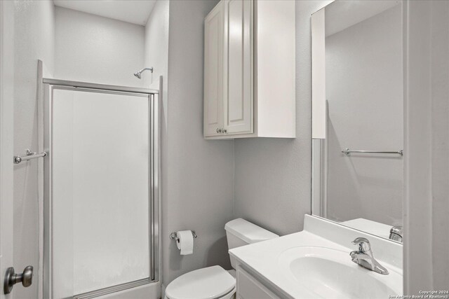 bathroom with a shower with shower door, vanity, and toilet