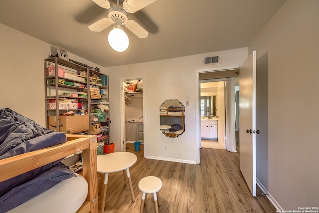 bedroom featuring a walk in closet, a closet, ceiling fan, and hardwood / wood-style floors