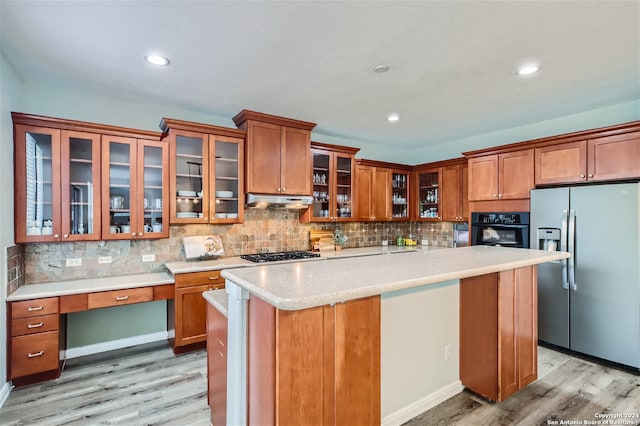 kitchen featuring a kitchen island, stainless steel appliances, light hardwood / wood-style floors, and tasteful backsplash