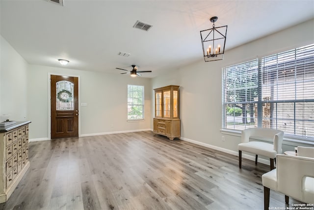 entryway with light wood-type flooring, ceiling fan with notable chandelier, and a wealth of natural light