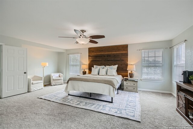 carpeted bedroom featuring ceiling fan and wooden walls