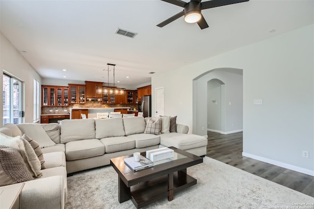 living area featuring baseboards, visible vents, arched walkways, wood finished floors, and recessed lighting