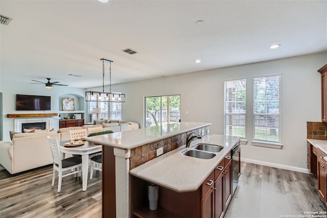 kitchen with dishwashing machine, a kitchen island with sink, light hardwood / wood-style floors, sink, and ceiling fan