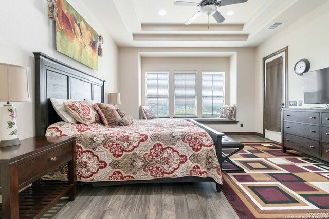 bedroom with a raised ceiling, ceiling fan, and hardwood / wood-style floors