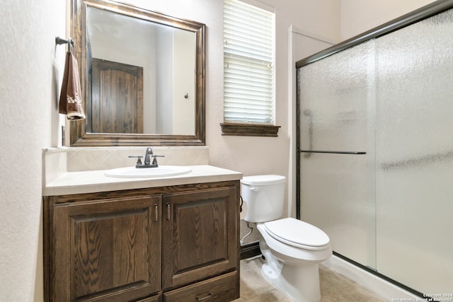 bathroom featuring tile patterned floors, vanity, walk in shower, and toilet