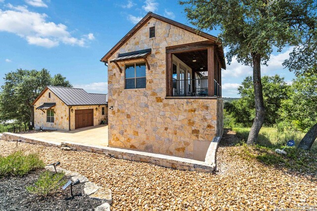 2204 Sierra Madre, Canyon Lake, TX 78133 - view of front of property with a garage, stone siding, metal roof, a standing seam roof, and concrete driveway
