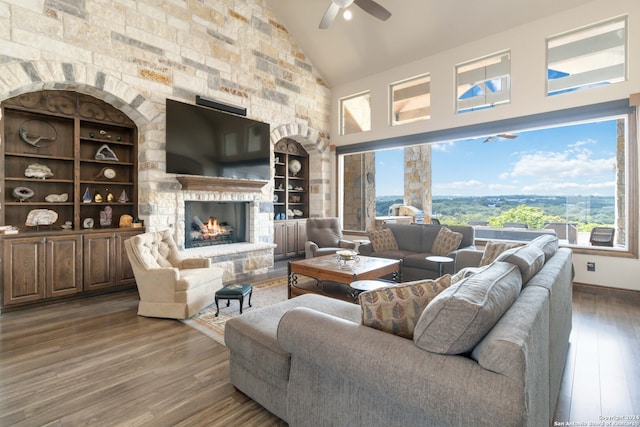 living room with ceiling fan, hardwood / wood-style flooring, high vaulted ceiling, and a fireplace