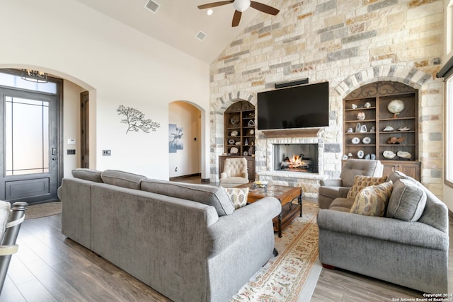 living room with built in shelves, a fireplace, high vaulted ceiling, wood-type flooring, and ceiling fan