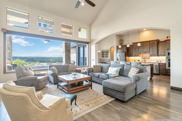 living room with ceiling fan, high vaulted ceiling, light hardwood / wood-style floors, and sink