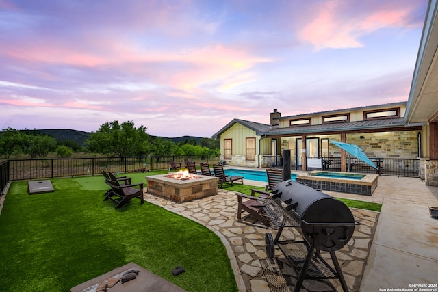 yard at dusk with a patio, an outdoor fire pit, and a swimming pool with hot tub