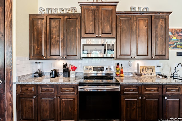 kitchen featuring appliances with stainless steel finishes, light stone counters, dark brown cabinets, and tasteful backsplash