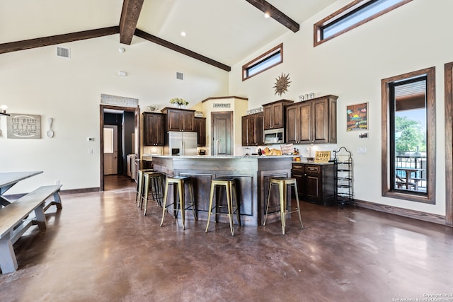 kitchen featuring a large island with sink, high vaulted ceiling, appliances with stainless steel finishes, and dark brown cabinets