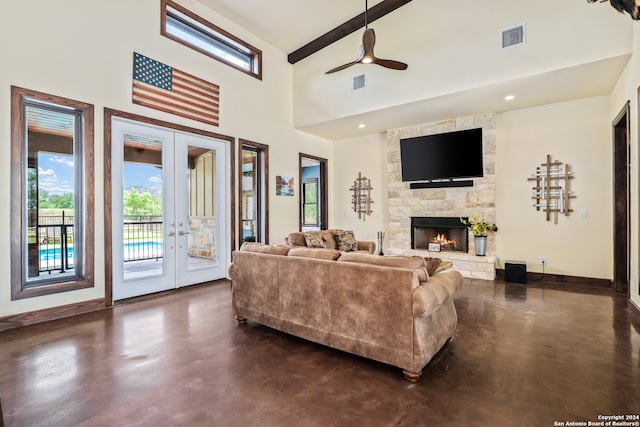 living room featuring ceiling fan, a fireplace, french doors, and beam ceiling