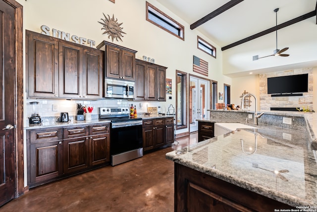 kitchen featuring beamed ceiling, appliances with stainless steel finishes, dark brown cabinets, light stone counters, and ceiling fan