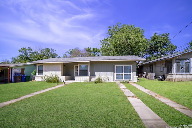 view of front facade with a front yard, brick siding, and central air condition unit