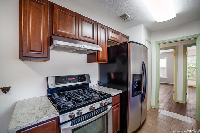 kitchen featuring appliances with stainless steel finishes, light stone counters, and light tile patterned flooring