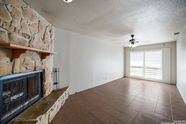 unfurnished living room with a fireplace, ceiling fan, a textured ceiling, and tile patterned floors